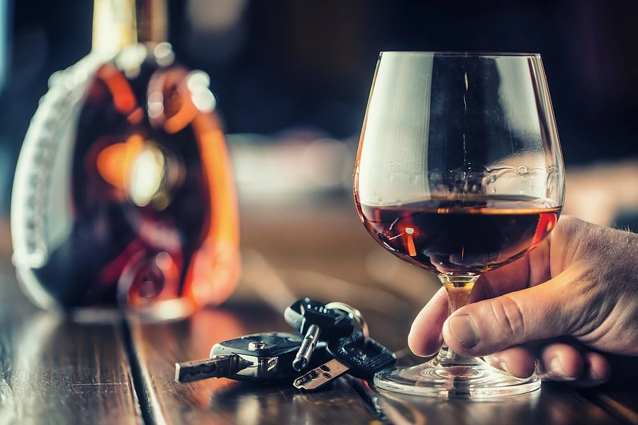 A set of car keys beside a glass of wine, symbolizing California DUI Laws for Out-of-State Drivers