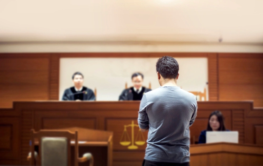 A person stands before a judge in a courtroom, representing legal consequences of aggravated drug trafficking